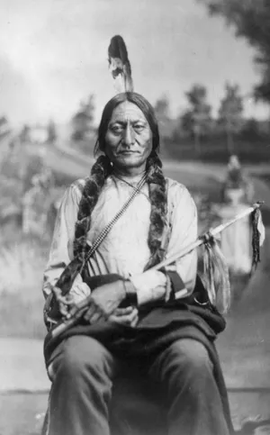 Sitting Bull sitting on a bench holding a weapon