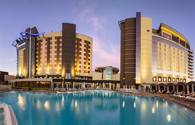 Exterior view of Wild Horse Pass Hotel & Casino at dusk, with illuminated hotel towers reflecting in a large outdoor pool
