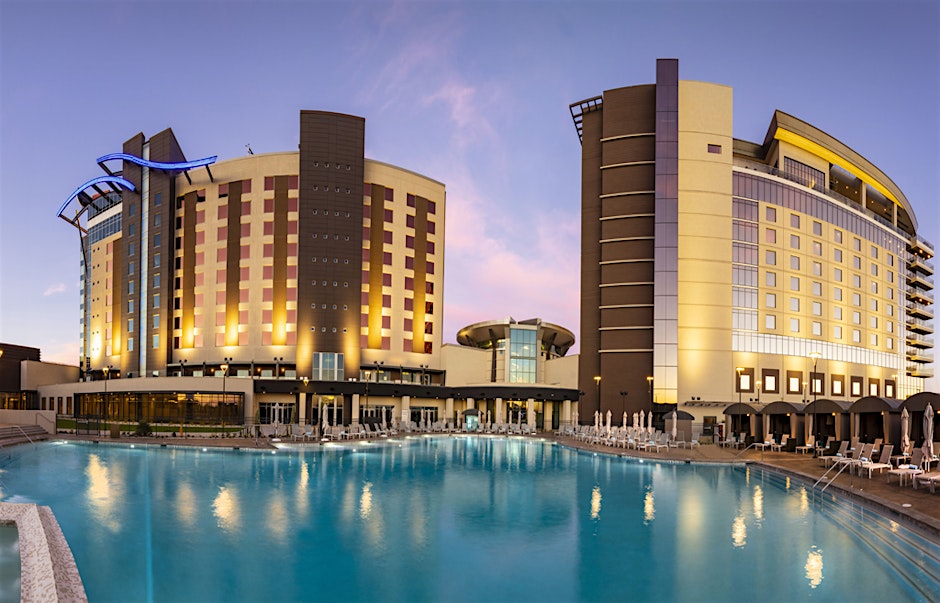 Exterior view of Wild Horse Pass Hotel & Casino at dusk, with illuminated hotel towers reflecting in a large outdoor pool