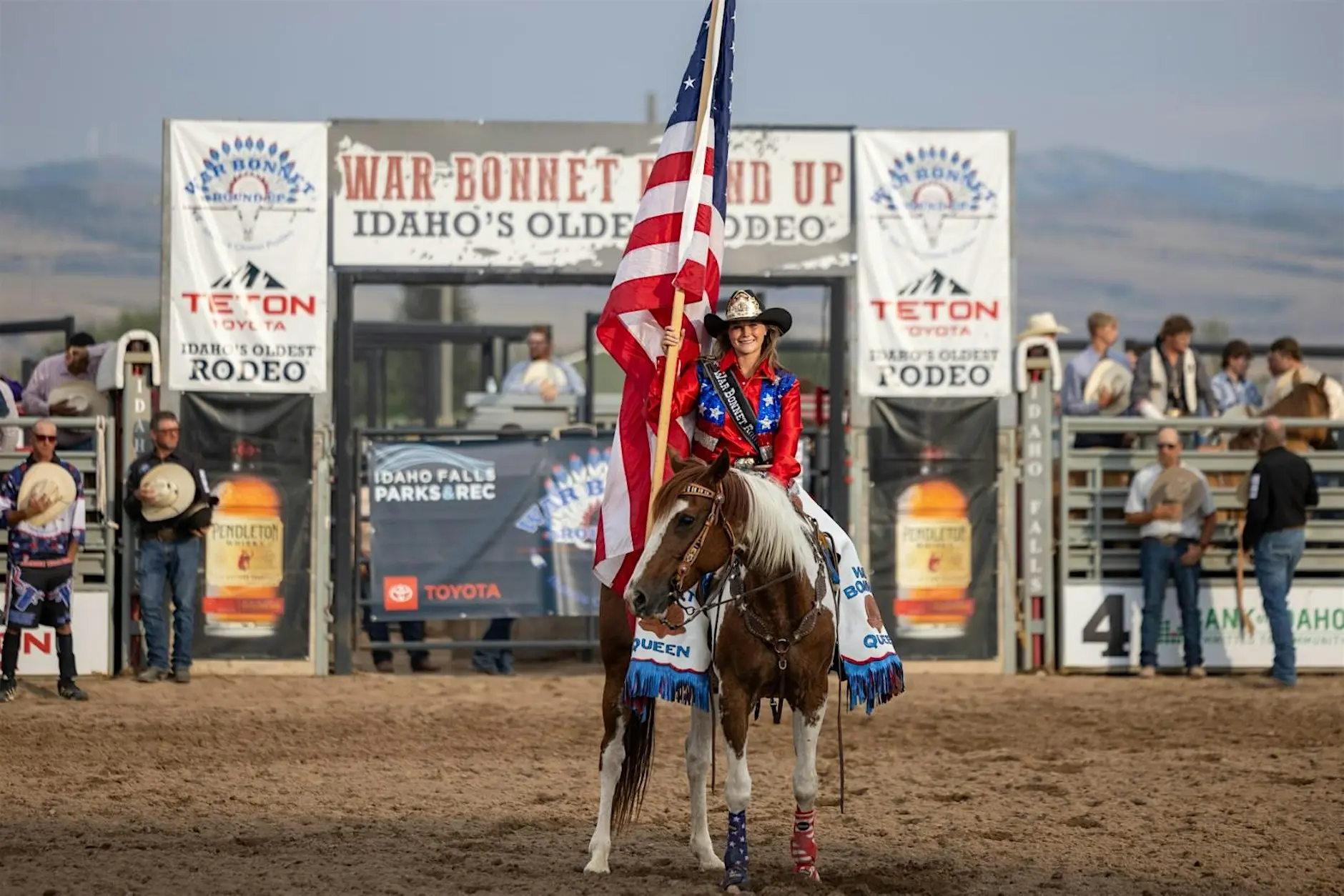 Rider on horseback carrying an American flag during the War Bonnet Round Up rodeo at Sandy Downs Arena in Idaho Falls.